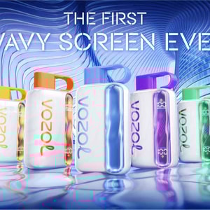 Row of colorful Vozol Star 40000 handheld devices with distinctive vertical wavy illuminated screens and loop handles, reflected on a rippling water-like surface against a futuristic blue wavy architectural background and a large headline reading “The First Wavy Screen Ever”.